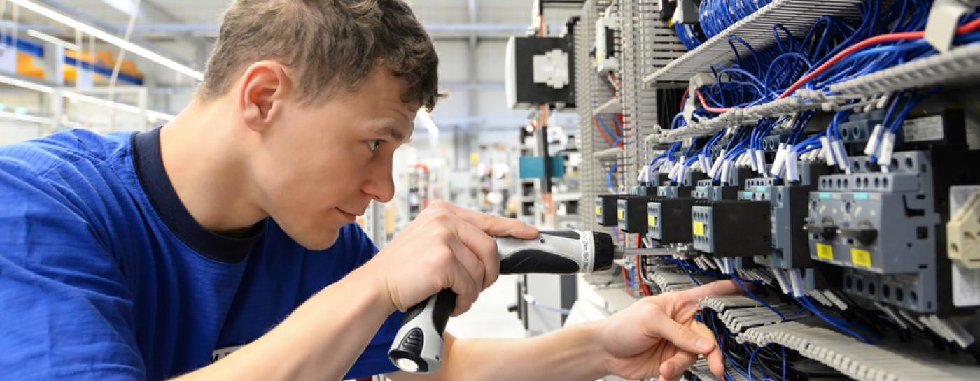 Ein Elektriker an einem Steuerungskasten Ein Elektriker an einem Steuerungskasten
